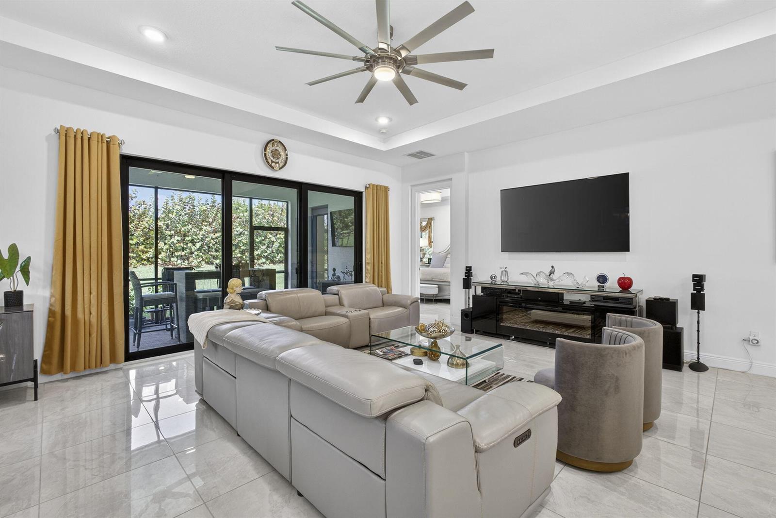 An open-concept living and dining area features gray furniture, a glass table, and modern lighting — 5492 St Armands Way, Westlake FL 33470, WESTLAKE, FL
