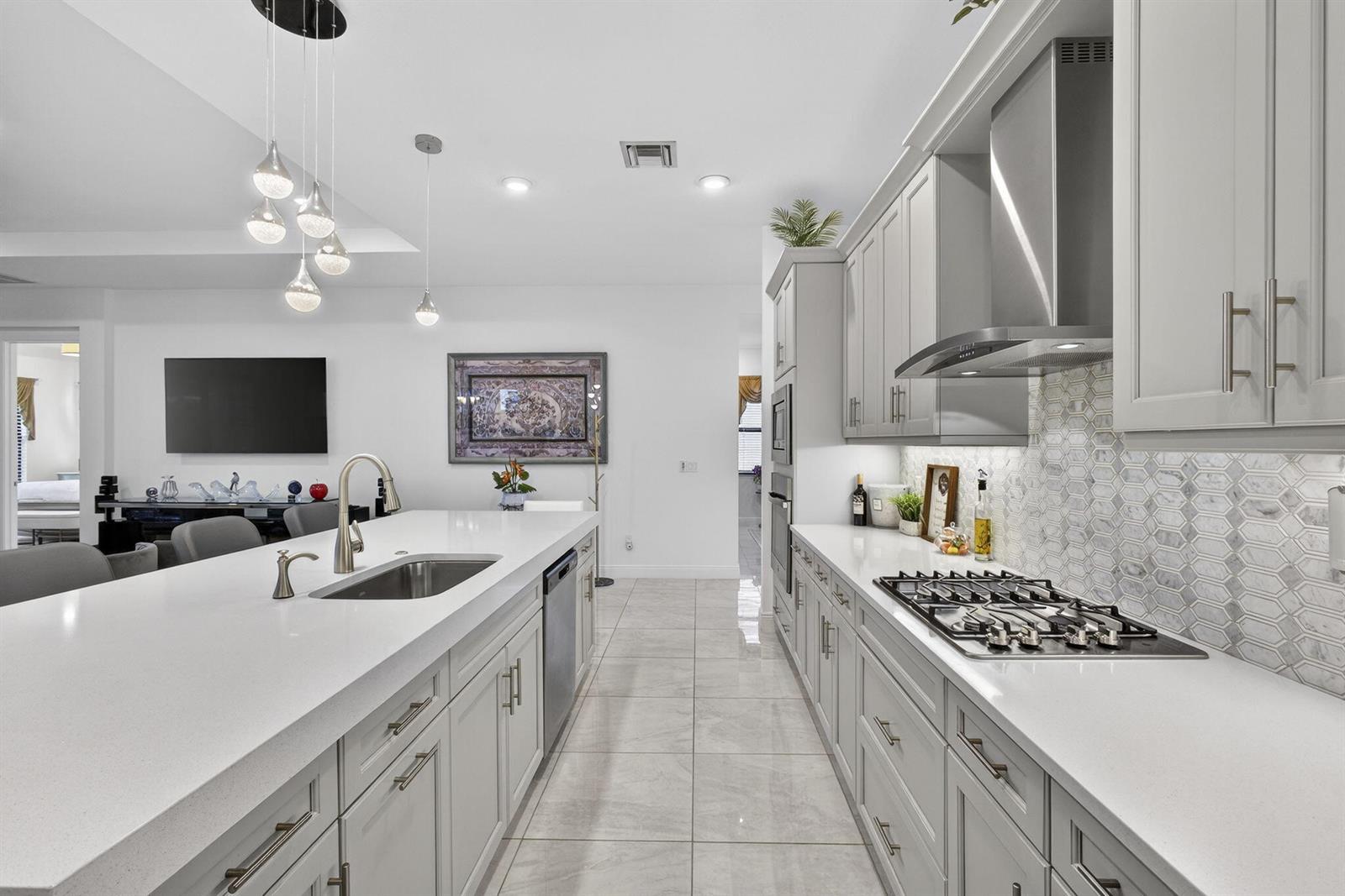 A modern kitchen features gray cabinetry, white quartz countertops, a large island, and tile flooring — 5492 St Armands Way, Westlake FL 33470, WESTLAKE, FL