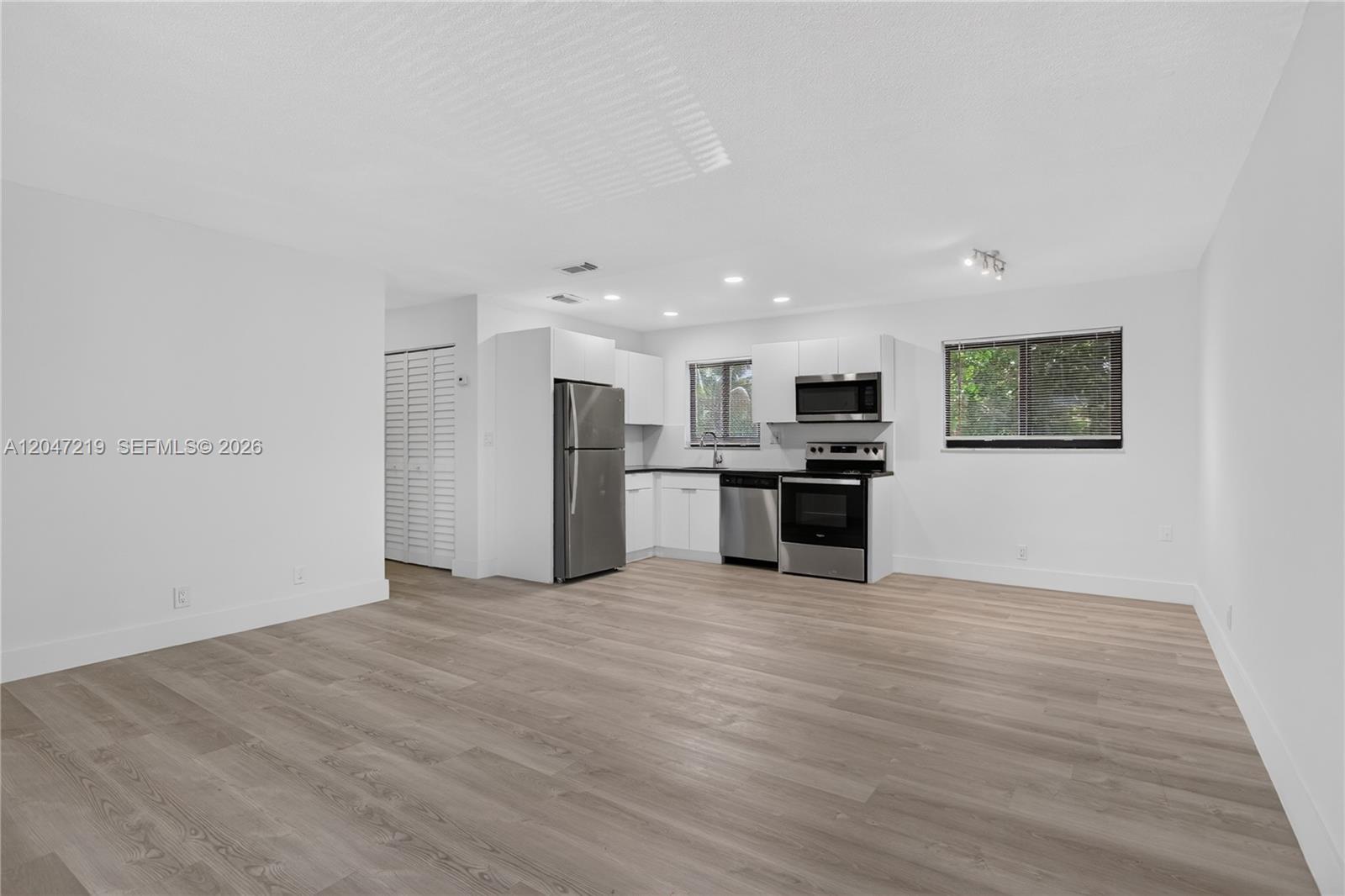 This kitchen features stainless steel appliances, white cabinetry, and light wood-look flooring — 615 NE 26TH ST # 7, Wilton Manors FL 33305, WILTON MANORS, FL