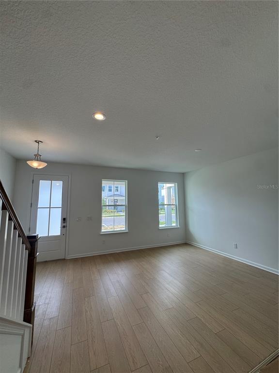 An interior view of a living area with light wood-look flooring, white walls, and windows — 1860 CROWNCREST DRIVE, APOPKA, FL