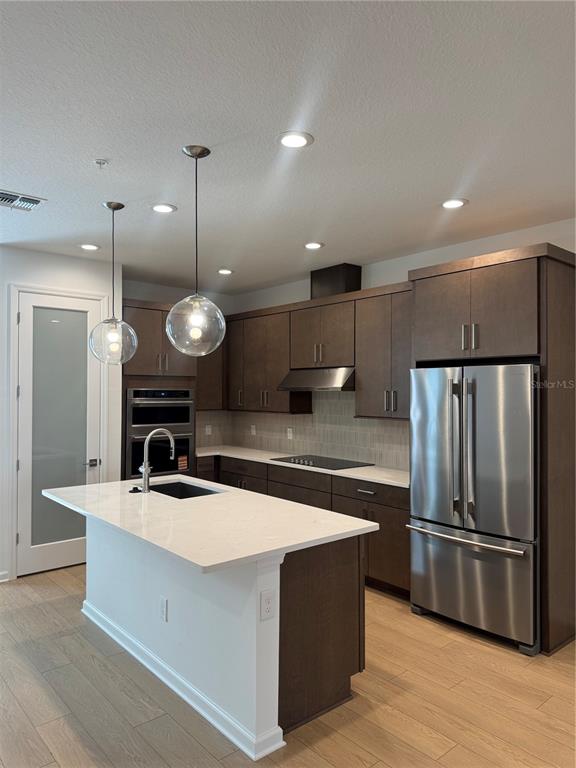 A modern kitchen features dark wood cabinetry, a white quartz island, and stainless steel appliances — 1860 CROWNCREST DRIVE, APOPKA, FL