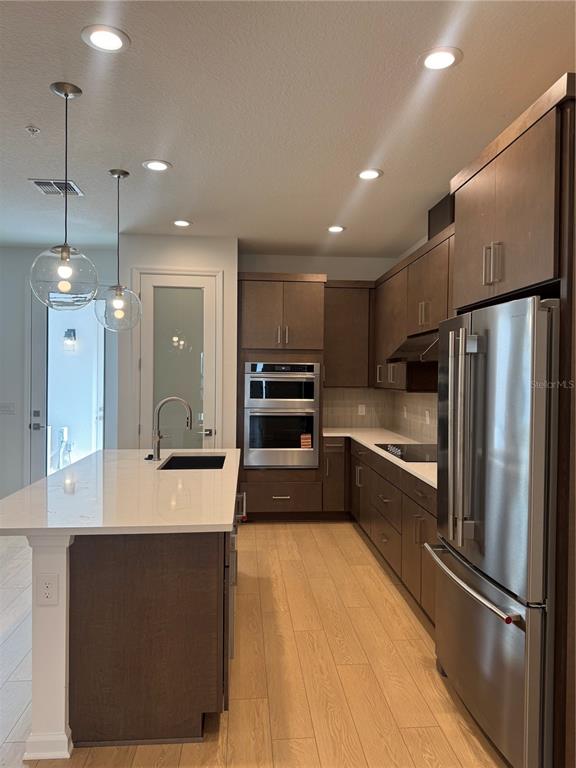 A modern kitchen features dark wood cabinetry, stainless steel appliances, and a white quartz island — 1860 CROWNCREST DRIVE, APOPKA, FL