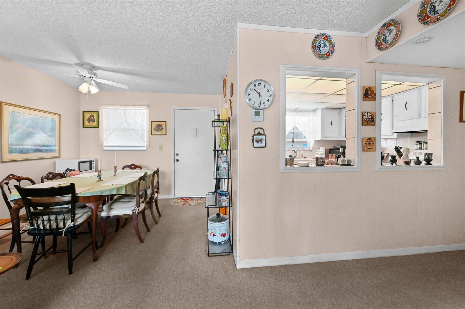 A dining area with a table and chairs next to a kitchen pass-through window — 721 Lori Drive # 313, Palm Springs FL 33461, PALM SPRINGS, FL