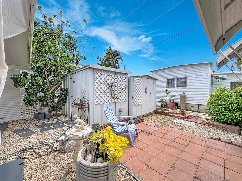 A backyard patio features a paved area, a blue chair, and two small storage sheds — 7490 46TH AVENUE N UNIT 109, ST PETERSBURG, FL