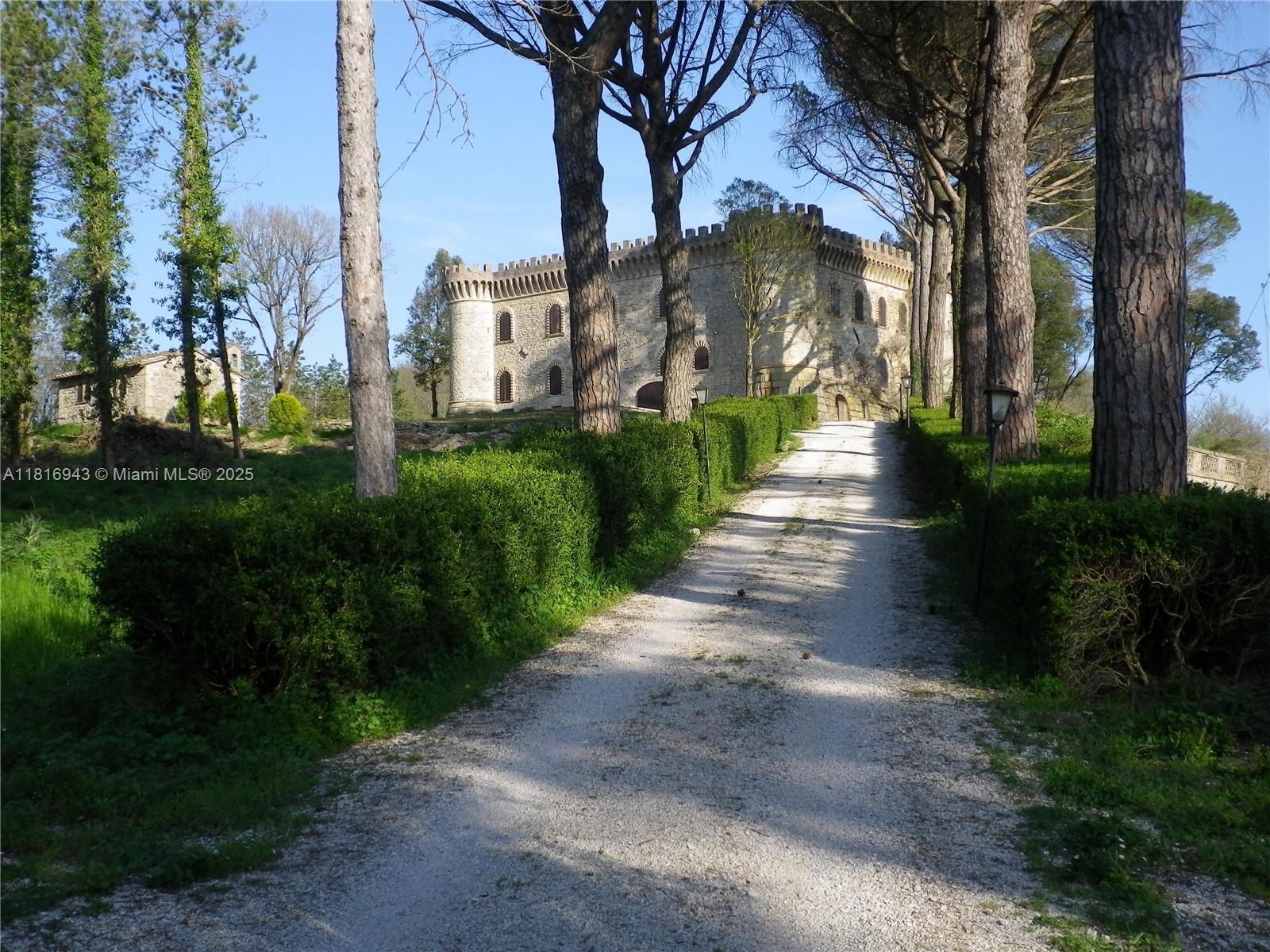 A gravel driveway leads toward a stone castle surrounded by tall trees and manicured hedges — Assisi Frazione S. Gregorio, 0, 0