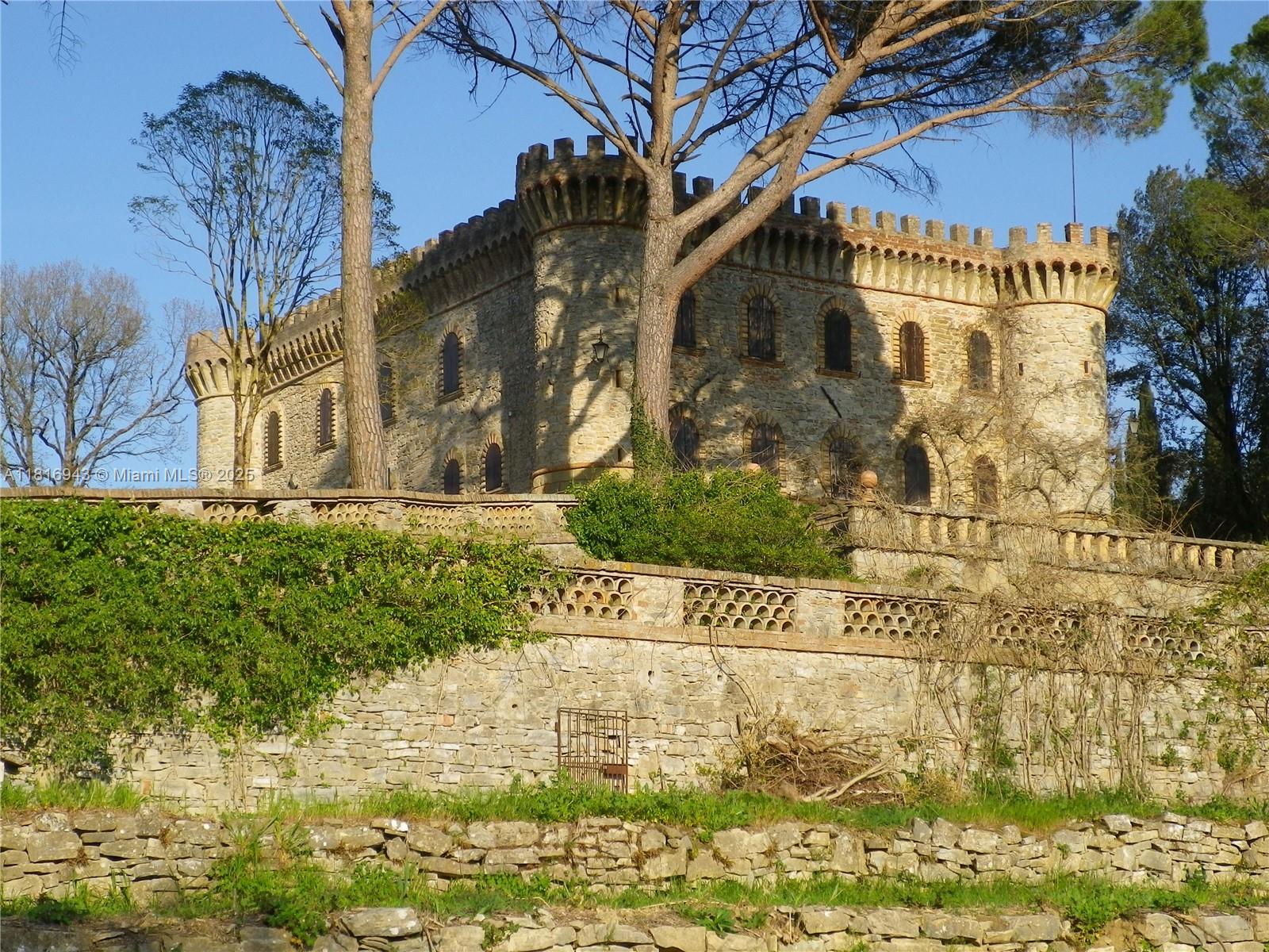 A stone castle with crenellated towers and arched windows sits atop a terraced hillside — Assisi Frazione S. Gregorio, 0, 0