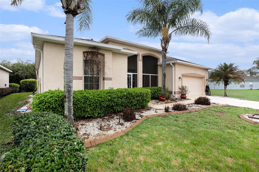 A covered, screened-in patio features concrete flooring, three ceiling fans, and a view of greenery — 9916 CLEGHORN DRIVE, SAN ANTONIO, FL