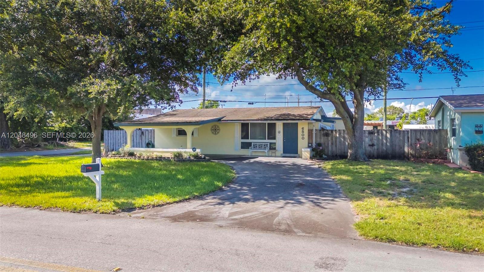 A single-story yellow house with a front porch, driveway, and large trees in the yard — 6500 Fletcher St, Hollywood FL 33023, HOLLYWOOD, FL