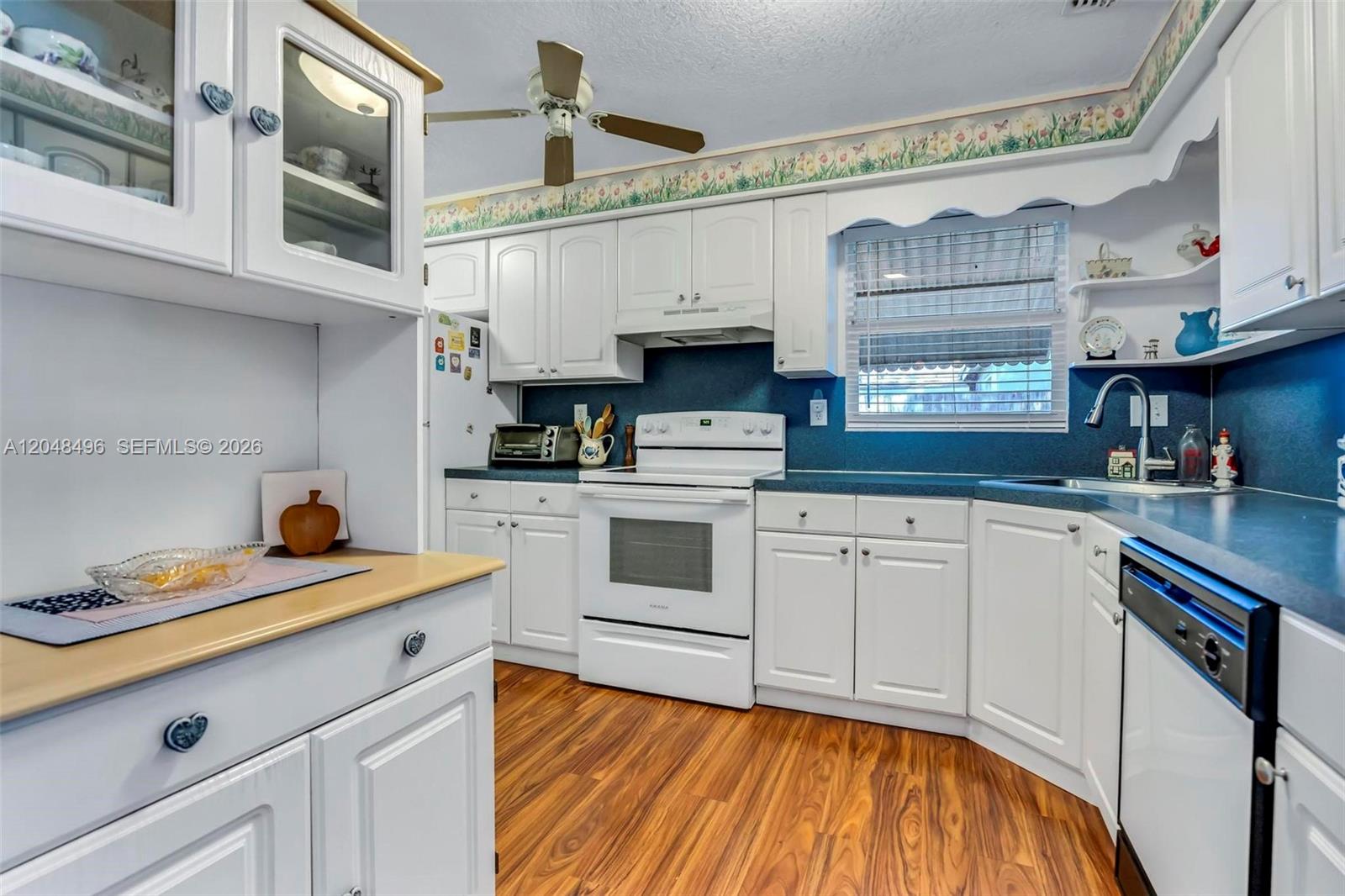 A kitchen features white cabinets, blue countertops, a white stove, and wood-look flooring — 6500 Fletcher St, Hollywood FL 33023, HOLLYWOOD, FL