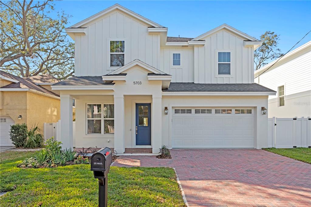 A two-story white house with a blue front door and a brick driveway — 4316 S RENELLIE DRIVE, TAMPA, FL