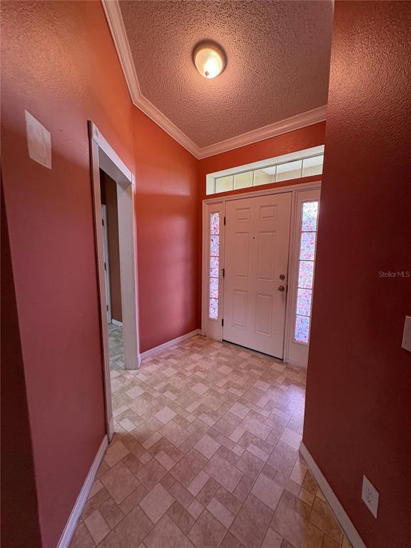An entryway features terracotta-colored walls, a tiled floor, a white front door, and a ceiling light — 104 HERRING LANE, POINCIANA, FL
