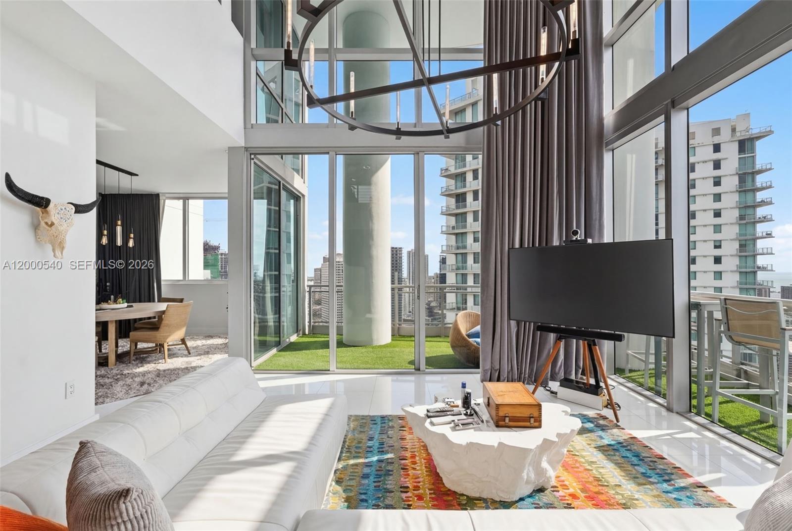 A modern living room features floor-to-ceiling windows, a white sofa, and a balcony with turf — 90 SW 3rd St # 12, Miami FL 33130, MIAMI, FL