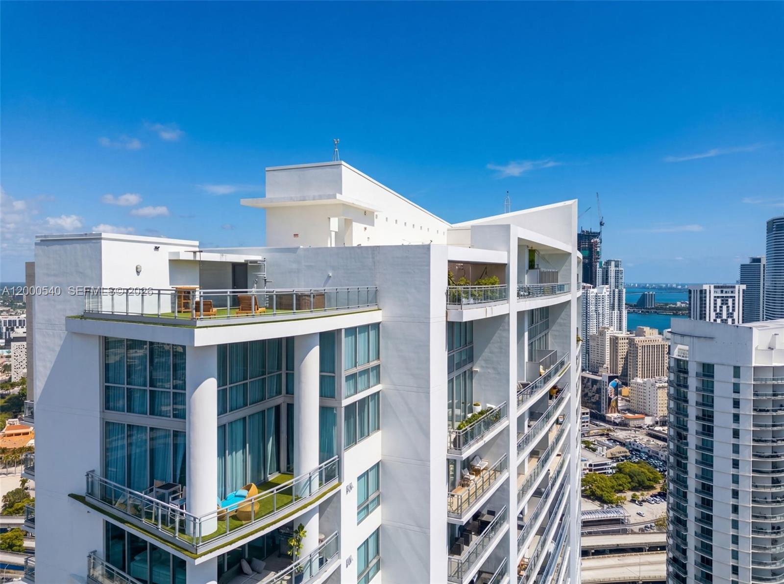 An exterior view of a high-rise building featuring multiple balconies and a rooftop terrace — 90 SW 3rd St # 12, Miami FL 33130, MIAMI, FL