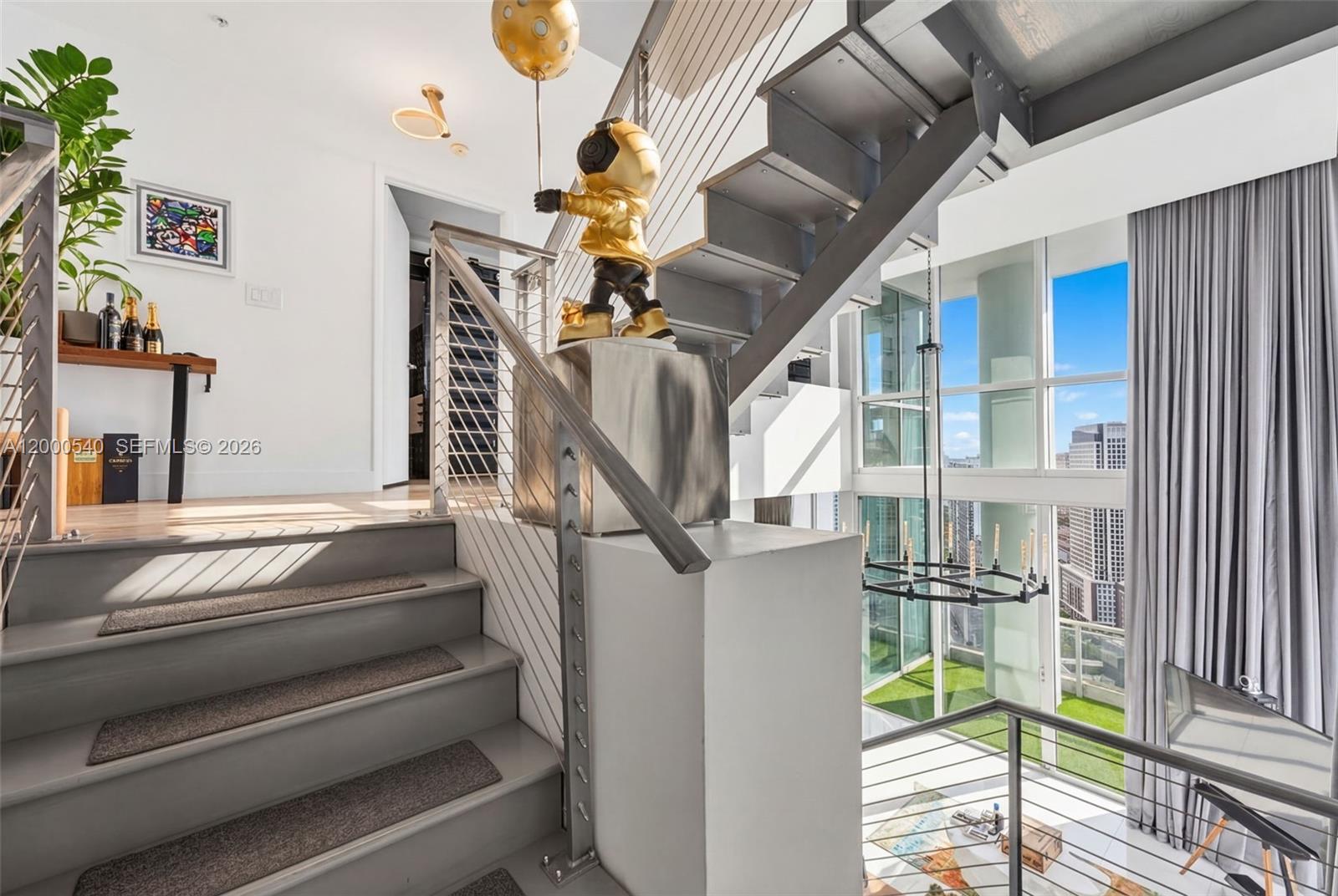 A modern staircase with metal railings leads to an upper level featuring a gold sculpture — 90 SW 3rd St # 12, Miami FL 33130, MIAMI, FL