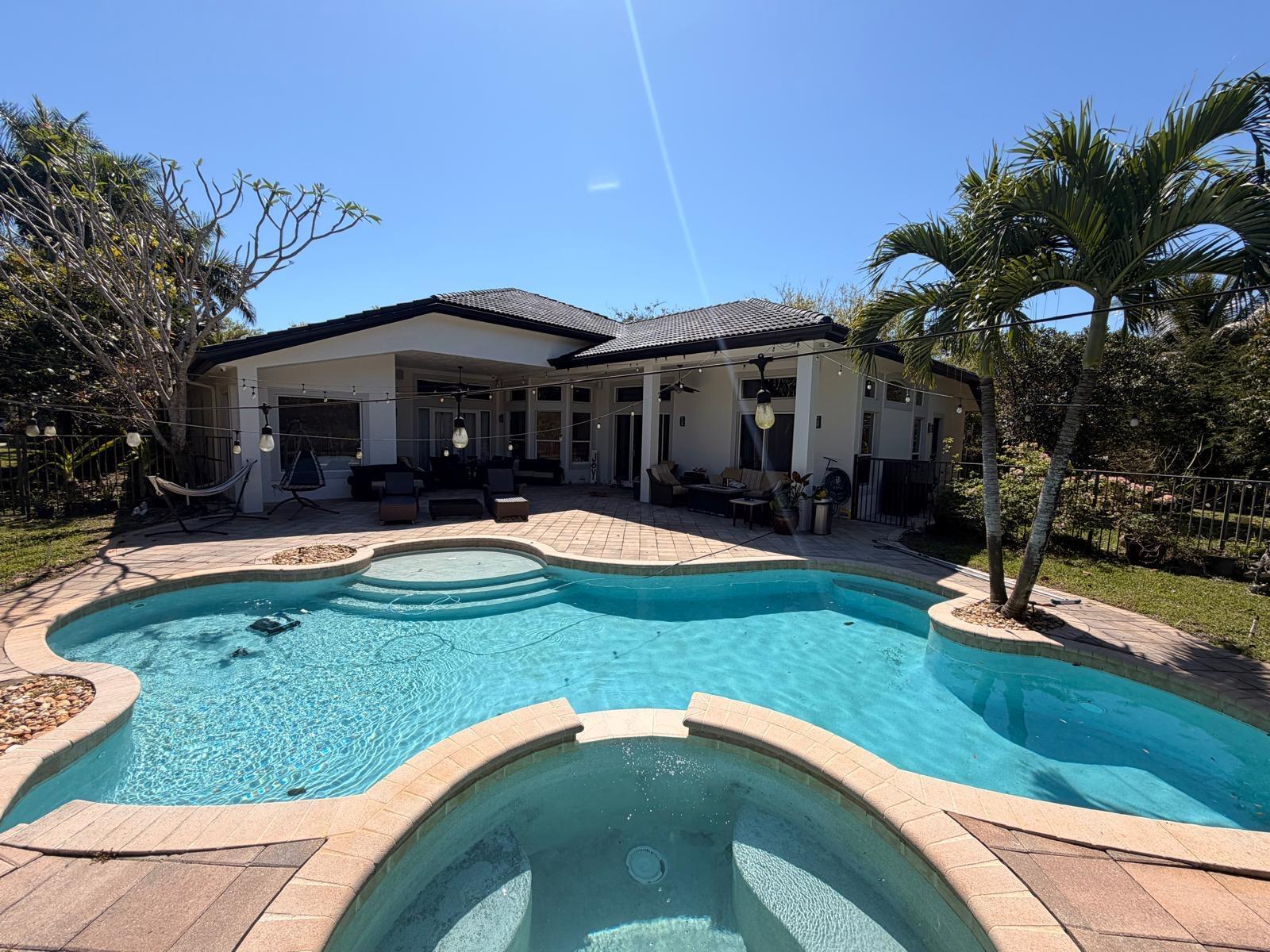 A backyard features a swimming pool, a hot tub, and a covered patio with outdoor furniture — 3309 Bradenham Lane, Davie FL 33328, DAVIE, FL