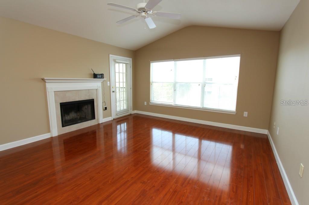 A living room features hardwood floors, a fireplace, a ceiling fan, and large windows — 18517 BRIDLE CLUB DRIVE UNIT 18517, TAMPA, FL