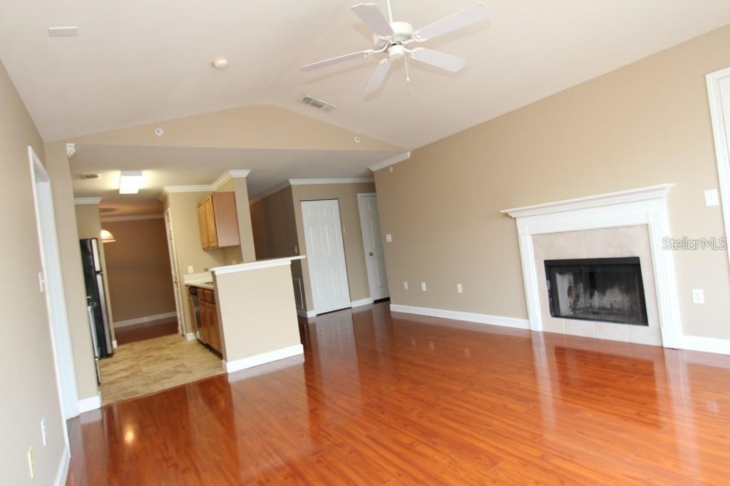 A living room with hardwood floors, a fireplace, and an adjacent kitchen area — 18517 BRIDLE CLUB DRIVE UNIT 18517, TAMPA, FL