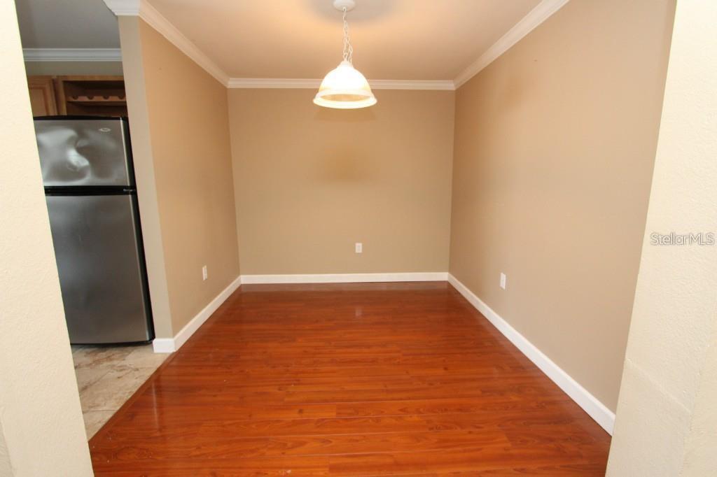 A dining area features hardwood flooring, beige walls, and a single pendant light fixture — 18517 BRIDLE CLUB DRIVE UNIT 18517, TAMPA, FL