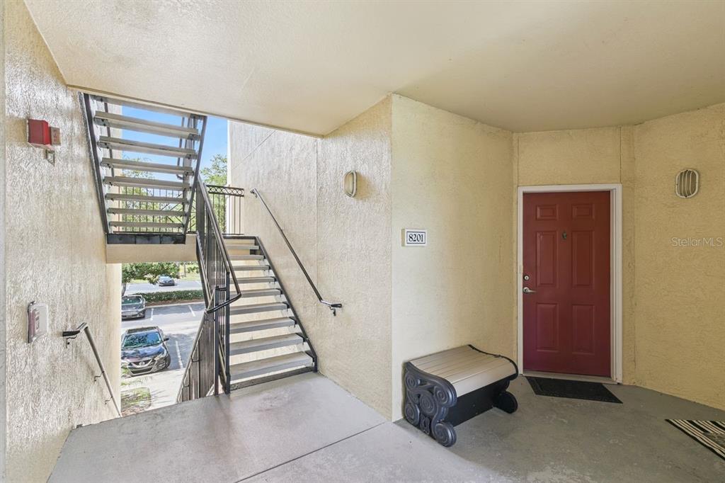 An exterior view of an apartment entrance with a red door and metal stairs — 1440 LAKE SHADOW CIRCLE UNIT 8201, MAITLAND, FL