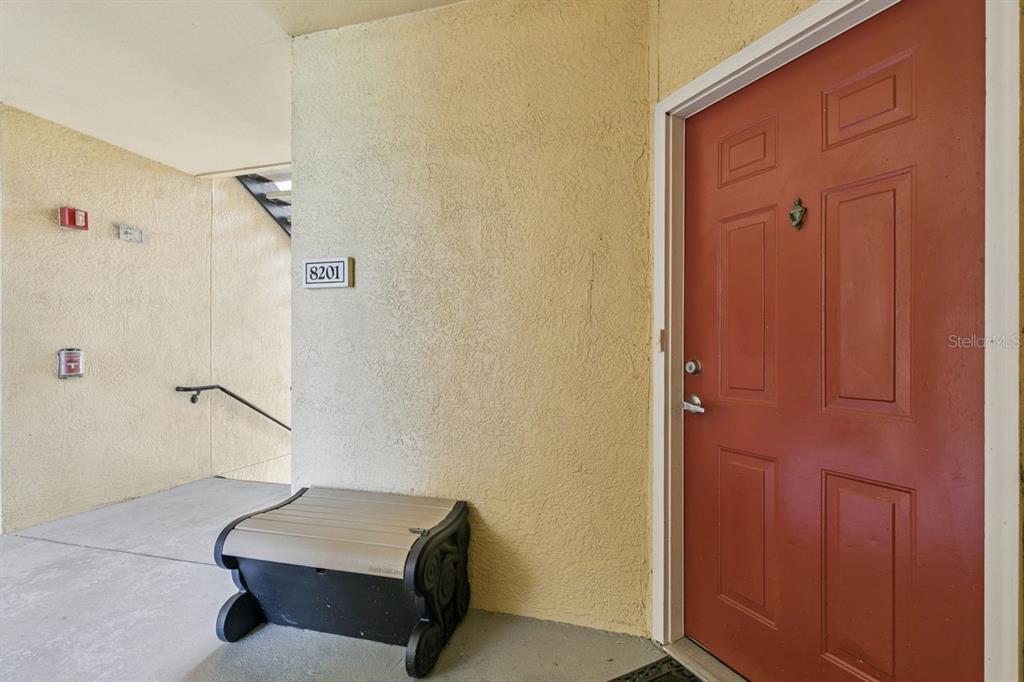 A red front door is adjacent to a beige wall with unit number 8201 — 1440 LAKE SHADOW CIRCLE UNIT 8201, MAITLAND, FL