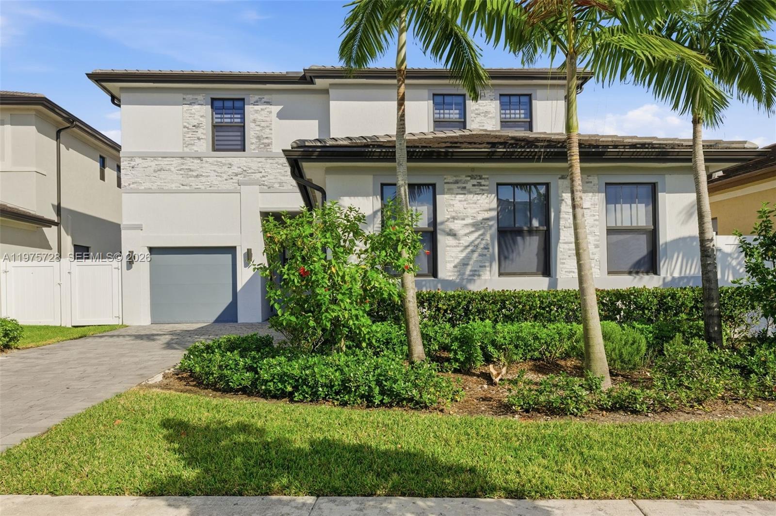 A two-story house features a gray garage, stone accents, and palm trees in the front yard — 4409 SW 173rd Ave, Miramar FL 33029, MIRAMAR, FL