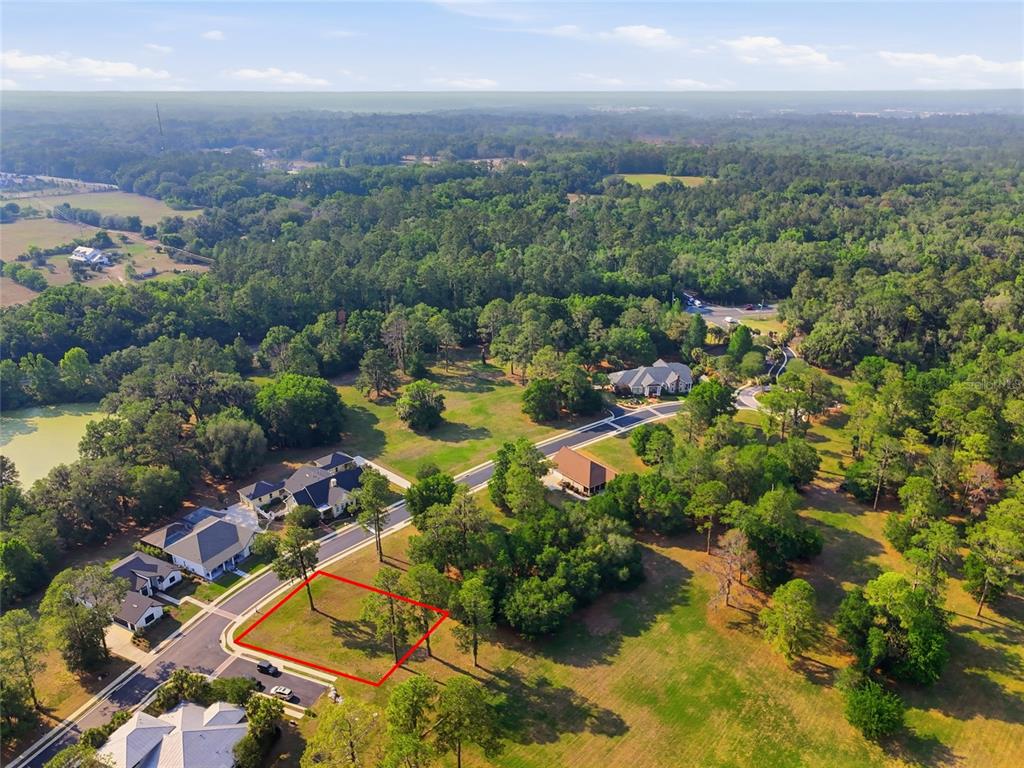 An aerial view shows a vacant residential lot outlined in red within a wooded neighborhood — 6723 SW 40TH TERRACE, GAINESVILLE, FL