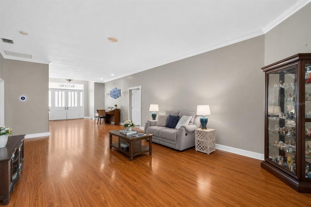 A living room features hardwood floors, a gray sofa, a coffee table, and a display cabinet — 421 WILLOW OAK COURT, FORT MEADE, FL