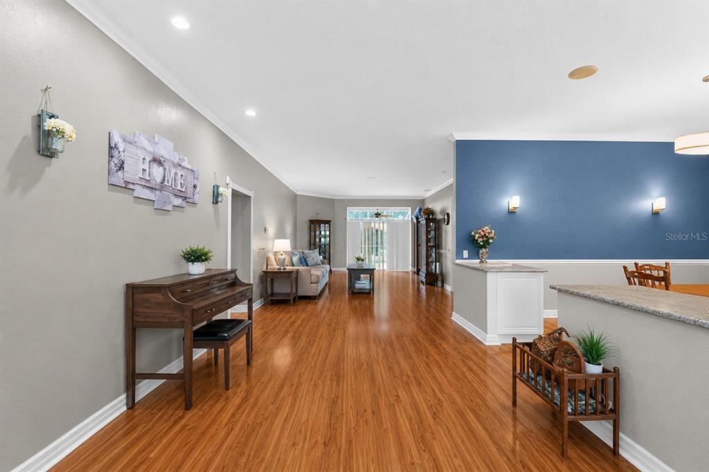 A living and dining area features wood-look flooring, a blue accent wall, and a piano — 421 WILLOW OAK COURT, FORT MEADE, FL
