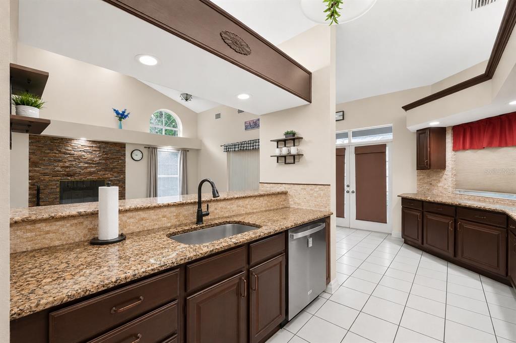 A kitchen with dark wood cabinets, granite countertops, and a stainless steel dishwasher — 421 WILLOW OAK COURT, FORT MEADE, FL