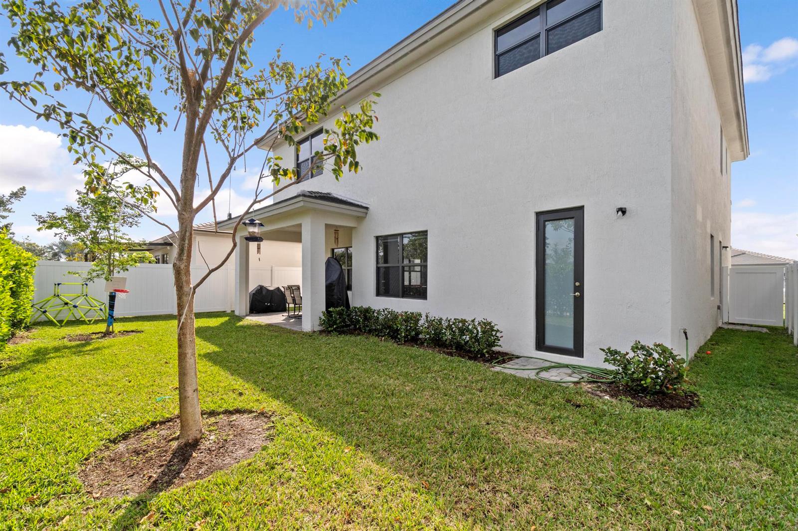 The exterior of a two-story white house features a covered patio and a grassy backyard — 17325 SW 41 Street, Miramar FL 33029, MIRAMAR, FL