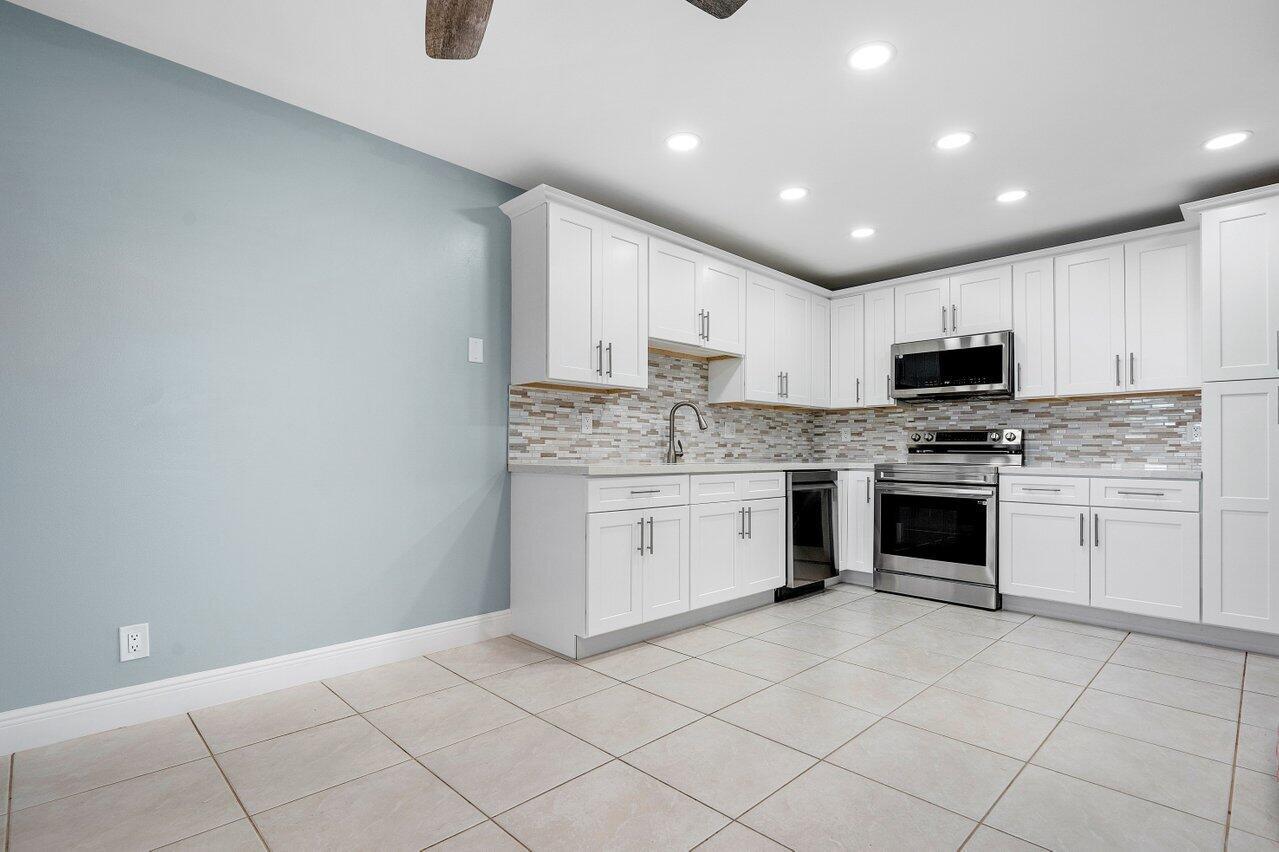 A kitchen with white cabinets, stainless steel appliances, and light-colored tile flooring — 1740 NW 19th Terrace # 204, Delray Beach FL 33445, DELRAY BEACH, FL