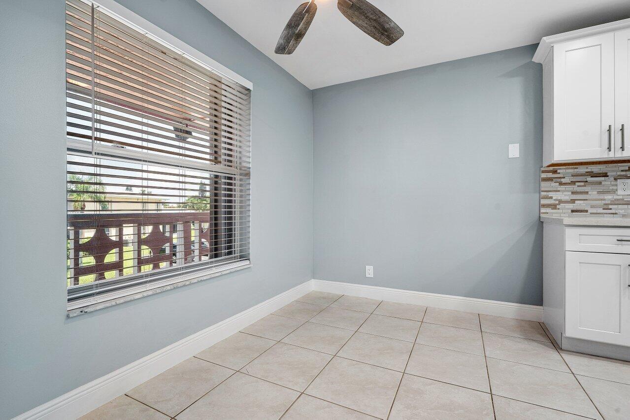 A dining area with light blue walls, tile flooring, a window with blinds, and white cabinets — 1740 NW 19th Terrace # 204, Delray Beach FL 33445, DELRAY BEACH, FL