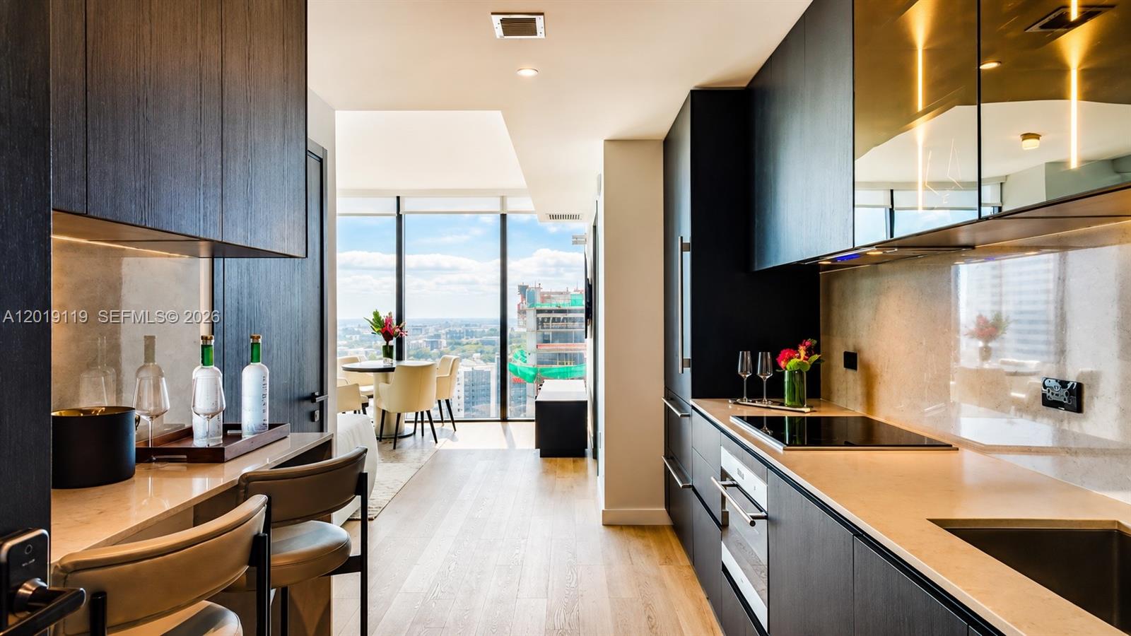 A modern kitchen features dark cabinetry, light countertops, and a view of the city skyline — 20 NE 11th St # 4406, Miami FL 33132, MIAMI, FL