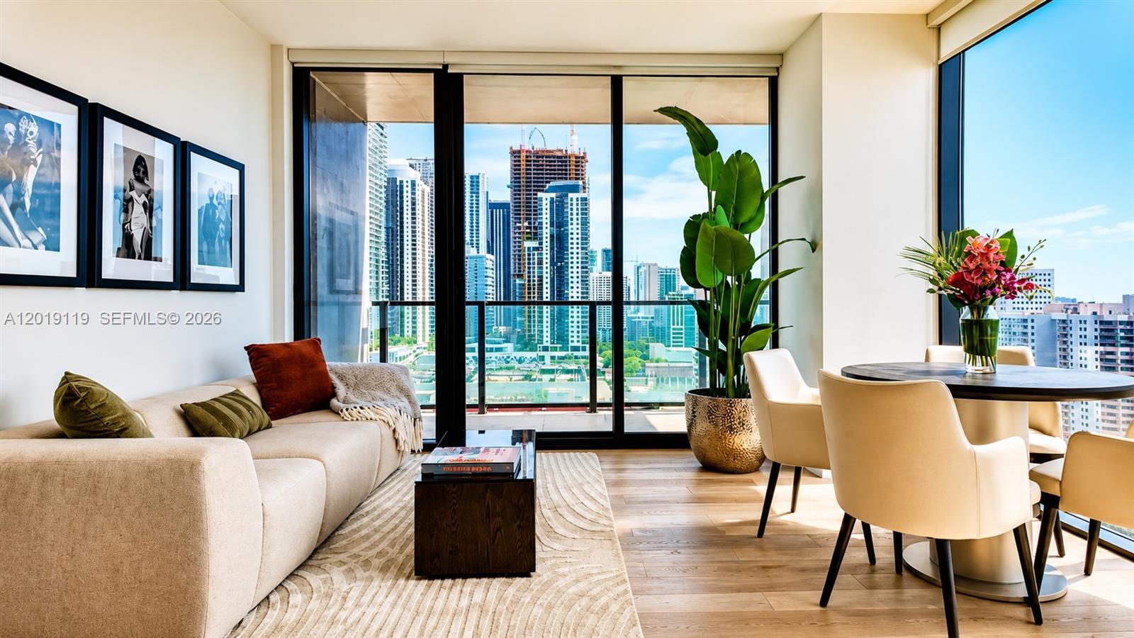 A living and dining area features a sofa, floor-to-ceiling windows, and city skyline views — 20 NE 11th St # 4406, Miami FL 33132, MIAMI, FL