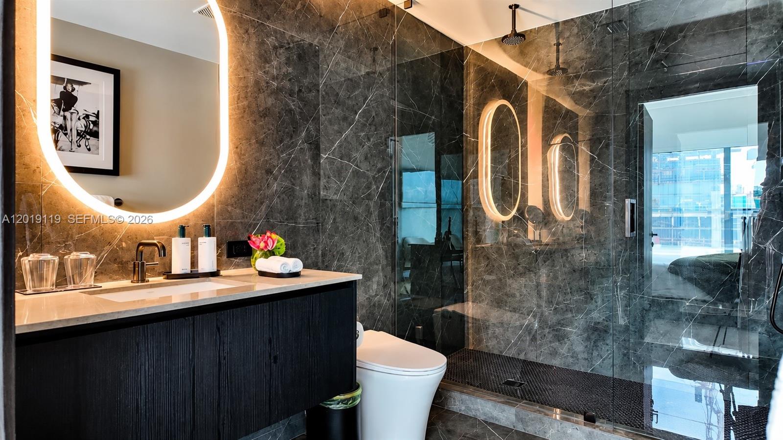 A modern bathroom features dark marble walls, a floating vanity, and a glass-enclosed shower — 20 NE 11th St # 4406, Miami FL 33132, MIAMI, FL