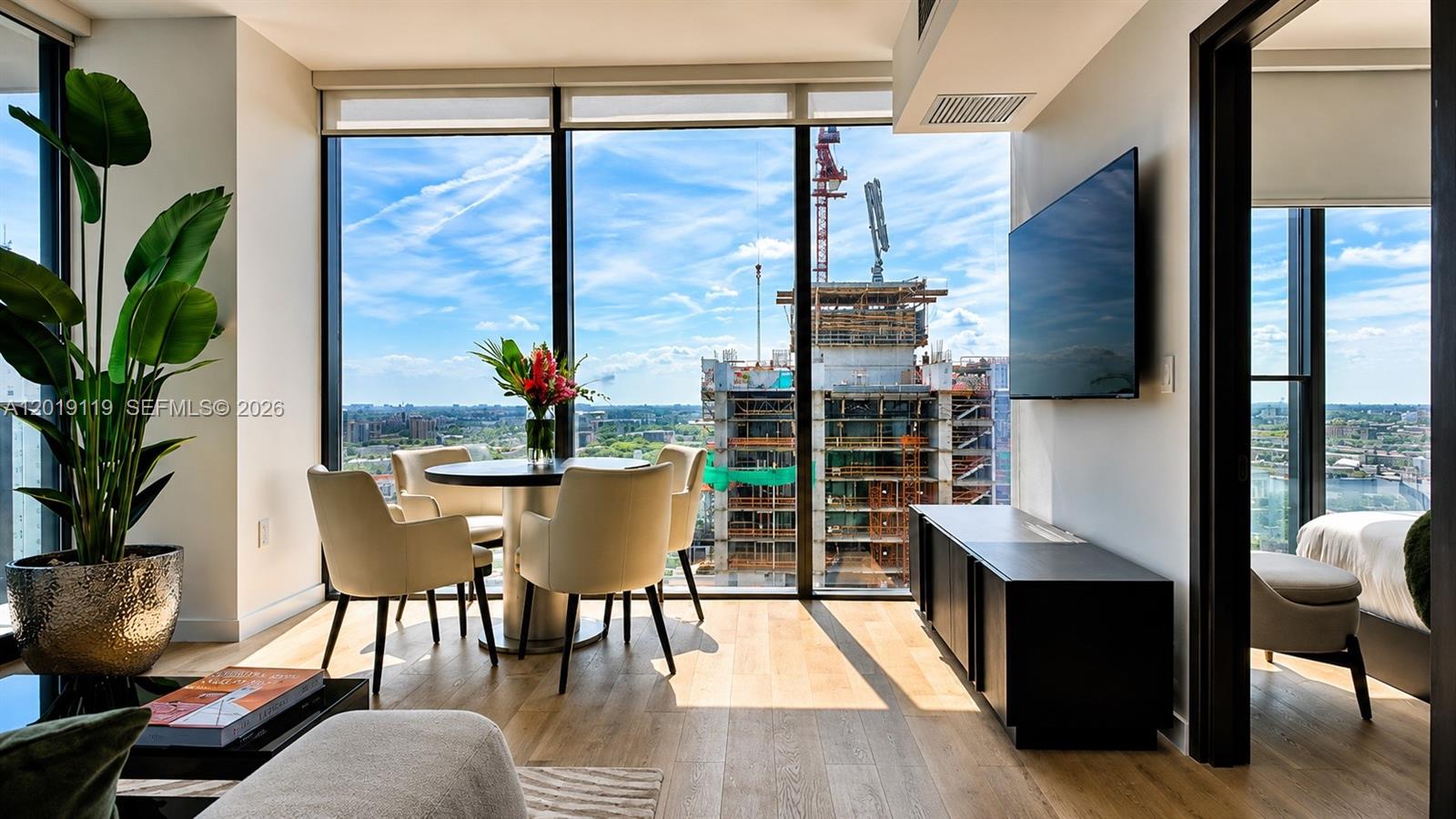 A dining area with floor-to-ceiling windows overlooking a construction site and city skyline — 20 NE 11th St # 4406, Miami FL 33132, MIAMI, FL