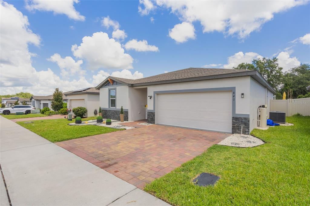 A single-story house features a two-car garage, a paver driveway, and a landscaped front yard — 840 TETON STREET, HAINES CITY, FL