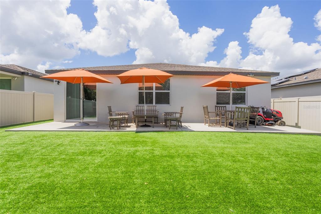 A backyard patio features three orange umbrellas, outdoor furniture, and a red riding lawnmower — 840 TETON STREET, HAINES CITY, FL