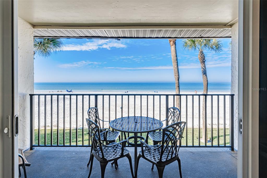 A balcony with a patio set overlooks a sandy beach and the ocean — 60 GULF BOULEVARD UNIT 203, INDIAN ROCKS BEACH, FL
