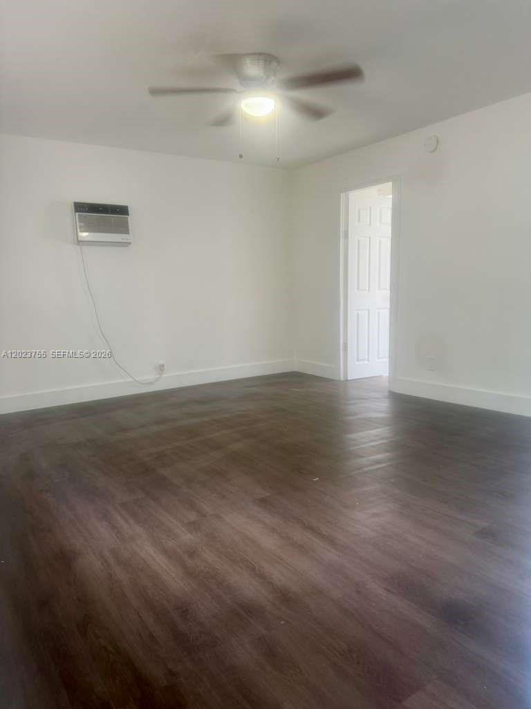 An empty room features dark wood-look flooring, white walls, a ceiling fan, and a wall-mounted air conditioner — 6026 SW 27th St # 1, Miramar FL 33023, MIRAMAR, FL