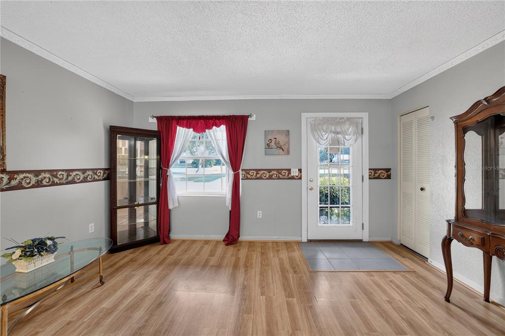 A living room features light wood flooring, gray walls with a decorative border, and a door — 2875 NE 49TH STREET, OCALA, FL