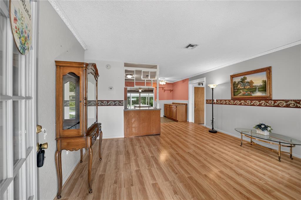 A living room with wood-look flooring, a wooden hutch, and a partial wall divider — 2875 NE 49TH STREET, OCALA, FL