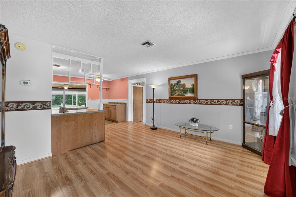 A living room with light wood flooring, gray walls, a decorative border, and a breakfast bar — 2875 NE 49TH STREET, OCALA, FL
