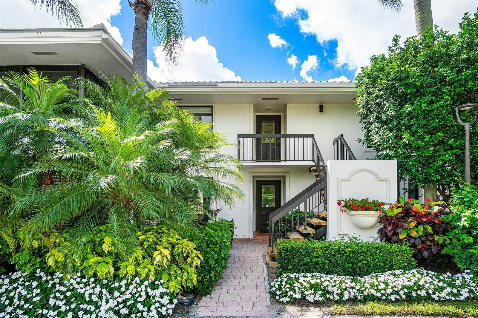 A two-story white building features a brick walkway, exterior staircase, and lush tropical landscaping — 3944 Quail Ridge Dr Drive N, Boynton Beach FL 33436, BOYNTON BEACH, FL