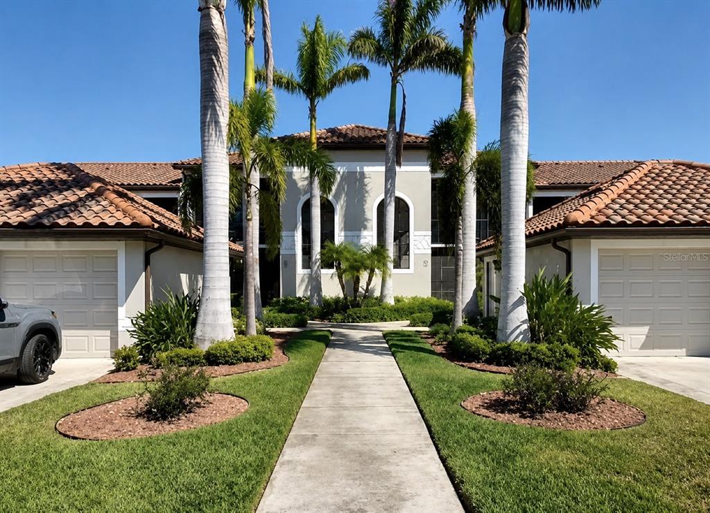 A teal front door with a small welcome mat sits in a recessed entryway — 6715 GRAND ESTUARY TRAIL UNIT 203, BRADENTON, FL