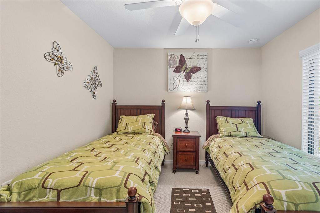 A bedroom features two twin beds with green patterned bedding and a central nightstand — 6715 GRAND ESTUARY TRAIL UNIT 203, BRADENTON, FL