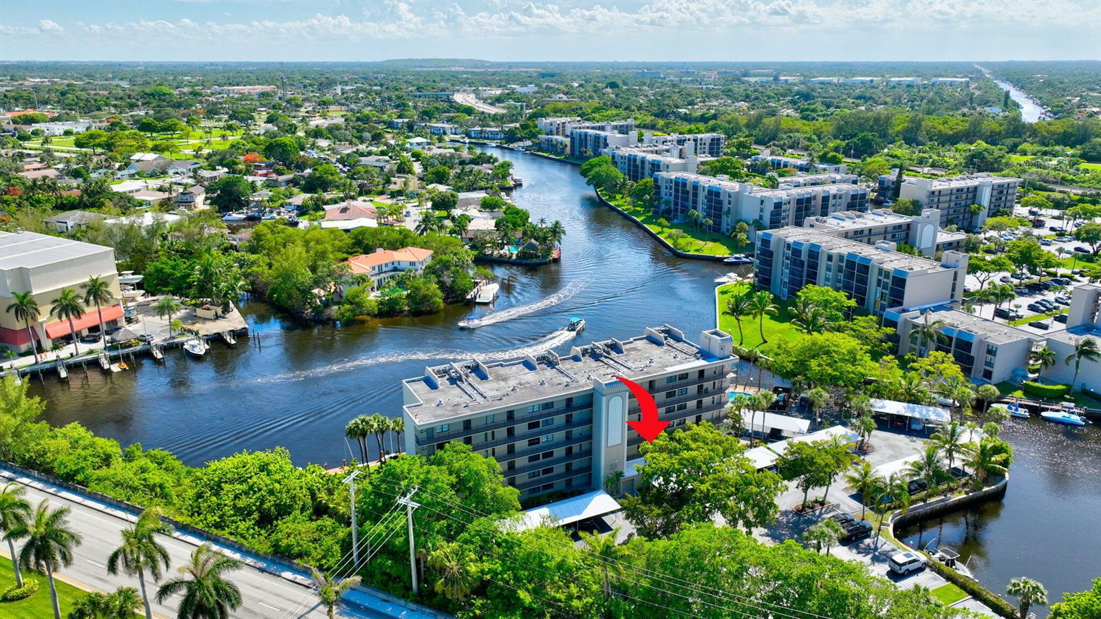 An aerial view shows a multi-story apartment building situated along a canal with boats — 22 Royal Palm Way # 606, Boca Raton FL 33432, BOCA RATON, FL