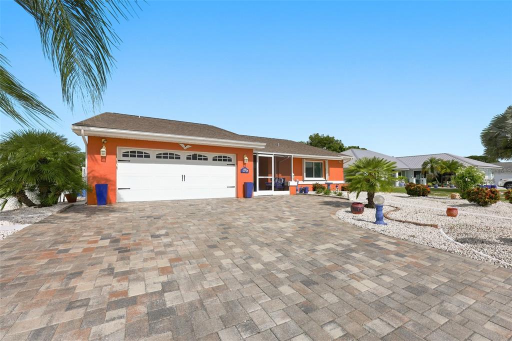 An orange house with a white garage door and a paved driveway under a blue sky — 1002 EL RANCHO DRIVE, SUN CITY CENTER, FL