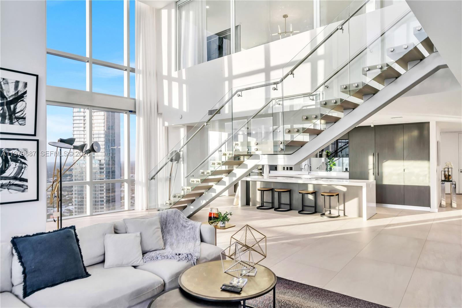 A modern, two-story living area features floor-to-ceiling windows, a glass-railed staircase, and a kitchen island — 851 NE 1st Avenue # 4612, Miami FL 33132, MIAMI, FL