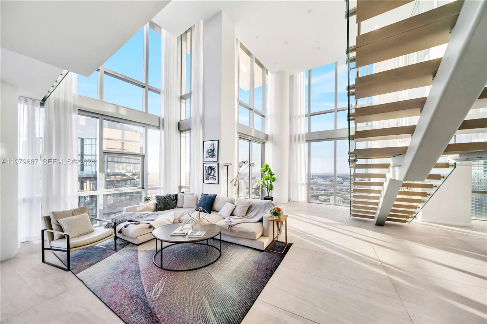 A modern living room features double-height windows, a floating staircase, and a large area rug — 851 NE 1st Avenue # 4612, Miami FL 33132, MIAMI, FL